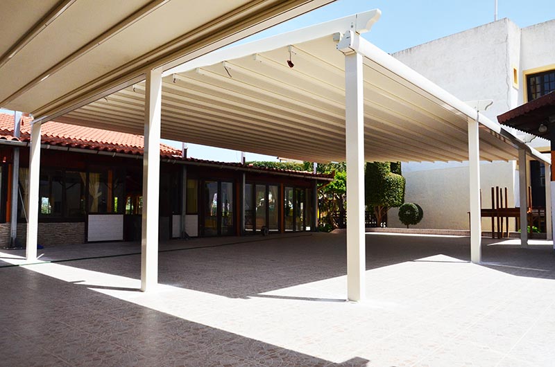 Awning-pergola structure with sockets for interior LED lighting and an assembled traditional gutter along the parapet